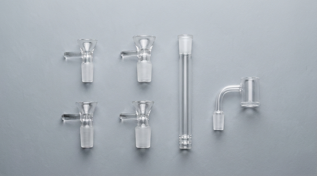 Glass bong bowls, downstem and quartz banger in different joint sizes on a gray background