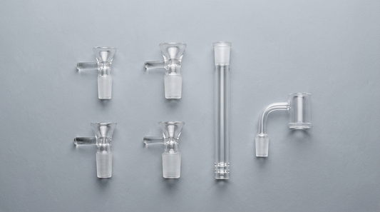 Glass bong bowls, downstem and quartz banger in different joint sizes on a gray background
