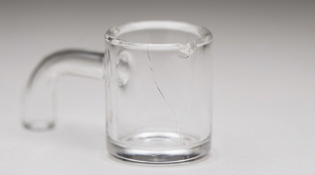 A clear quartz banger with a visible crack down the bucket and a chipped rim