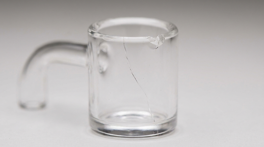 A clear quartz banger with a visible crack down the bucket and a chipped rim